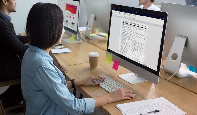 Woman working on a desktop computer in a shared office space