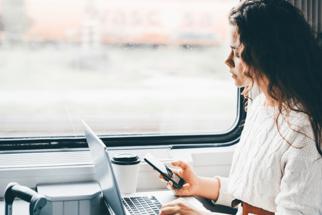 Woman on a train working with laptop and mobile